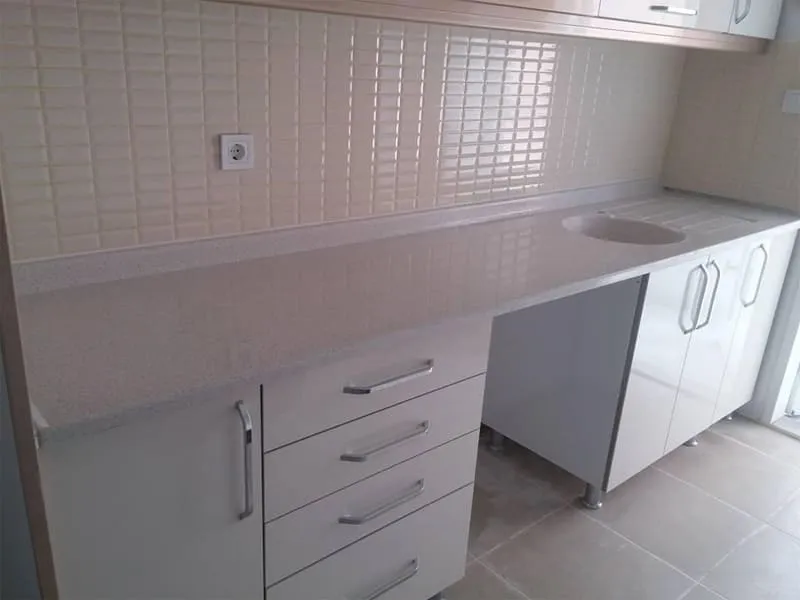 Açık gri mermerit tezgâh ve tek parça döküm evye, beyaz dolaplı mutfak
